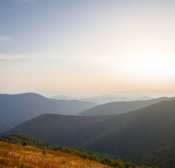 Naklejka na ściany i meble beautiful quiwt mountain valley at the sunset, mountain chain silhouette in a blue mist