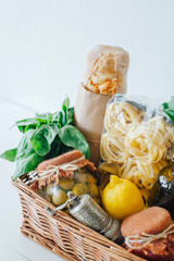 Italian food basket with bread, basil, olive oil, lemons, and a bottle of wine.