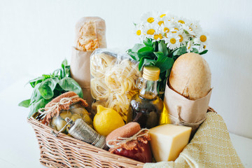 Italian food basket with bread, basil, olive oil, lemons, and a bottle of wine.
