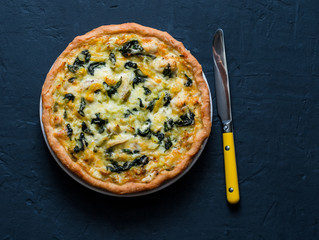 Chicken, leek, cheese, spinach quiche on dark background, top view