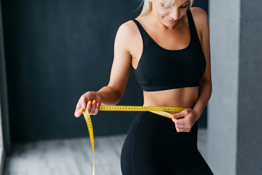 Athletic Slim Woman Measuring Her Waist By Measure Tape