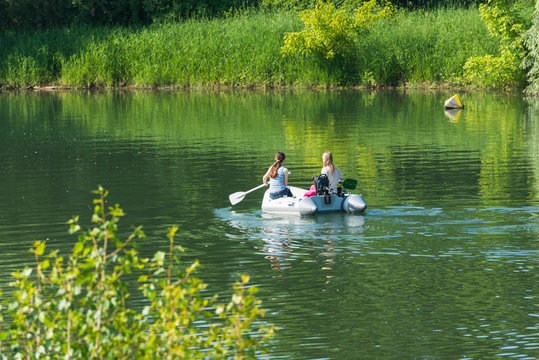 Zwei Mädchen paddeln in einem Schlauchboot auf einem See