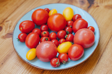 Plate of fresh ripe tomatoes on blue polka dot background