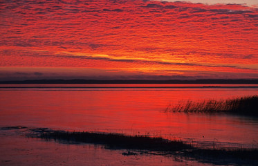 Sunset scene in late autumn. Temperature below zero and lake water began to freeze.