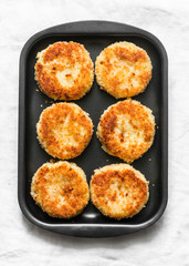 Potato bread crumbs baked cakes on a baking tray on a light background, top view