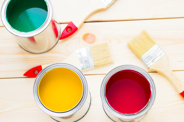 House renovation concept, colorfull paint cans and paintbrushes on wooden background