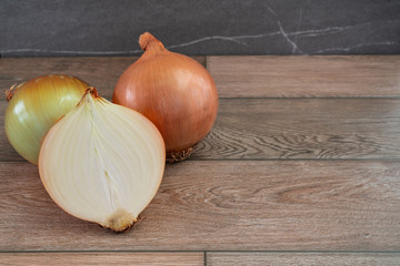 Onions on wooden and stone background.