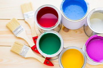 House renovation concept, colorfull paint cans and paintbrushes on wooden background