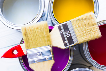 House renovation concept, colorfull paint cans and paintbrushes on wooden background