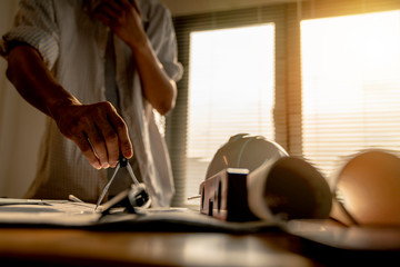 architect or civil engineer during drawing home or building in office on working table with office stationary , laptop ,color pallette sampling.