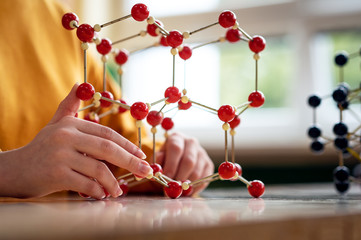 Female student holding molecular structure model. Science class concept.