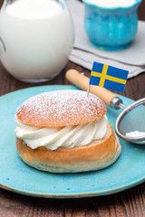 Traditional swedish dessert Semla or Shrove bun, with almond paste and whipped cream filling, served with milk, vertical