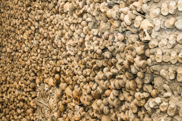The wall is made of human bones and skulls. Bones and skulls are arranged chaotically, fastened with cement.