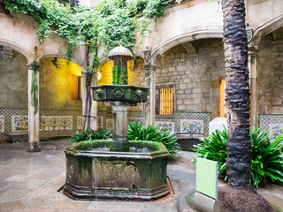Barcelona, Spain, Nov 1, 2018: Typical spanish courtryard or patio with fountain and greenary. Beautiful archs and walls made of stone. No people. - 244337821