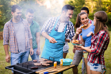 Happy friends enjoying barbecue party in forest