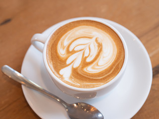 coffee latte in a white cup on wooden table in coffee shop.