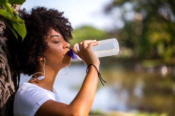 Fitness african model with a water bottle in the park - Imagem