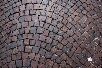 Semicircle pavement with square cobblestones. Stone road texture of red and brown granite bricks, ancient city street