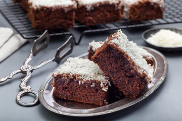 Homemade brownie with coconut flakes, swedish dessert Karleksmums, cut in square servings,...