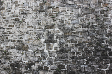 Close up of ancient dirty gray and black irregular bricks wall. Natural old stones walls texture