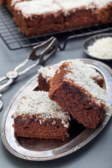 Homemade brownie with coconut flakes, swedish dessert Karleksmums, cut in square servings, vertical