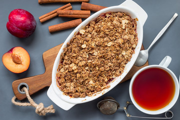 Plum crumble pie or plum crisp with oats and spices, in baking dish, top view, horizontal