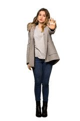 A full-length shot of a Teenager girl with coat making stop gesture denying a situation that thinks wrong on isolated white background