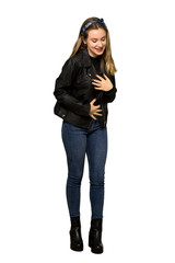 A full-length shot of a Teenager girl with leather jacket smiling a lot while putting hands on chest on isolated white background