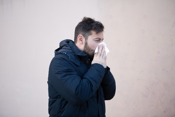Man sneezing in winter with hanky in hand