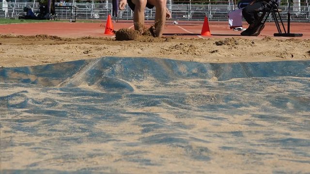 Sportsman landing into sandpit in long jump competition.