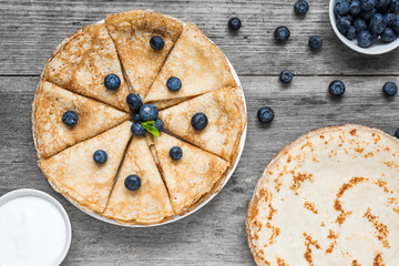 traditional russian pancakes or bliny with blueberries, sour cream and mint. Pile of thin homemade...