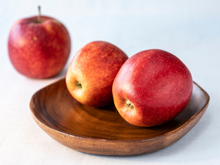 Three red apples on the wooden plate and white background