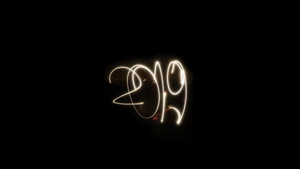 Happy New Year 2019. Sparkle background of the light written in 2019, isolated on the black background. Long banner for website and copy space for your personalised text.