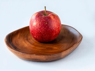 One red apple on the wooden plate and white background
