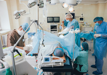 Process of trauma surgery operation. Group of surgeons in operating room with surgery equipment.