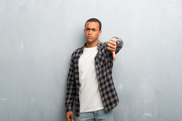 Young african american man with checkered shirt showing thumb down sign with negative expression