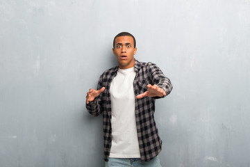 Young african american man with checkered shirt is a little bit nervous and scared stretching hands...