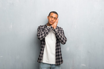 Young african american man with checkered shirt making sleep gesture in dorable expression