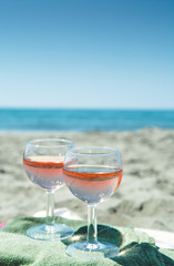 Beach party with sea view, romantic celebration on sunny sandy beach, two glasses with rose wine