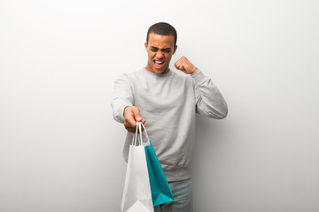 African american man on white wall background holding a lot of shopping bags