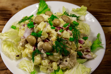 Potato salad with marinated mushrooms, eggs, red onion and mayonnaise on wooden table