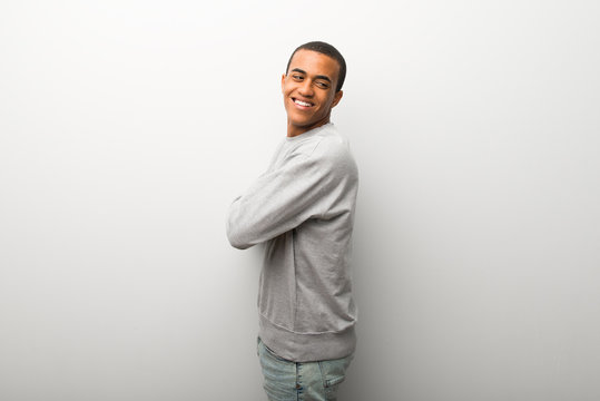 African american man on white wall background looking over the shoulder with a smile