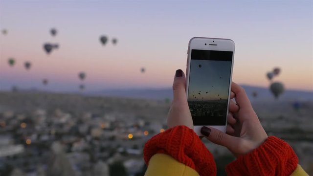close up, woman shoots a Cappadocia air balloon on her phone