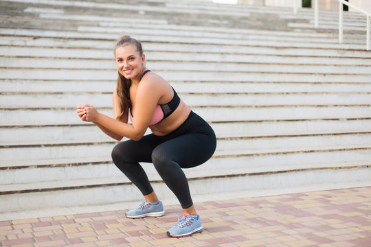 Young pretty smiling plus size woman in sporty top and leggings doing sport  with stairs on background Stock Photo | Adobe Stock