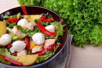 Salad with chicken, roasted potato, mozzarella cheese and red pepper in a bowl