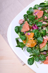Salad with radicchio, mandarins, red oranges and canned tuna on a white plate