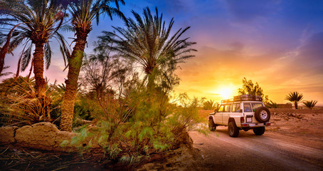 Travel, SUV rides a desert road at beautiful sunset, extreme travel adventure in nature