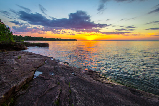 Scenic Summer Sunset. Sunset over the horizon of Lake Superior on a wild remote rocky coastline in Copper Harbor, Michigan.