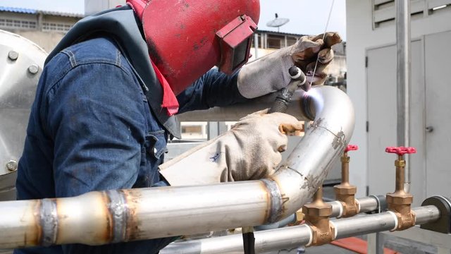 Welder arc welding metal stainless pipe for cooling water system in the factory