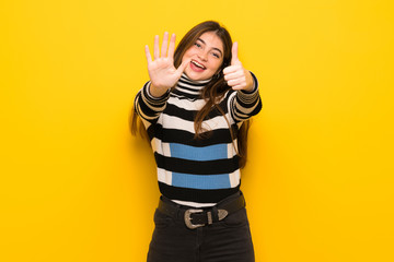 Young woman over yellow wall counting six with fingers